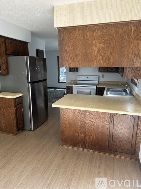 A kitchen with wooden cabinets and a black refrigerator.
