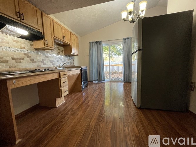 A kitchen with wooden floors and a black refrigerator.