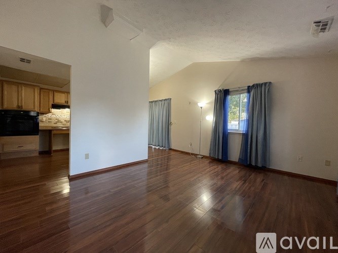 A room with wooden floors and a window with blue curtains.
