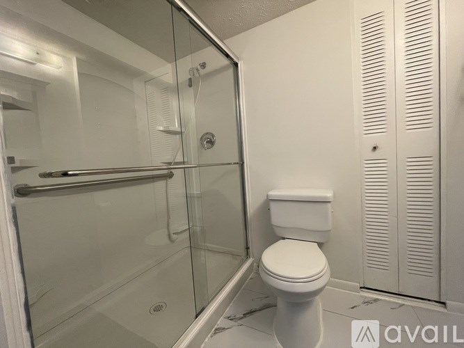A white toilet sits next to a walk-in shower in a bathroom.