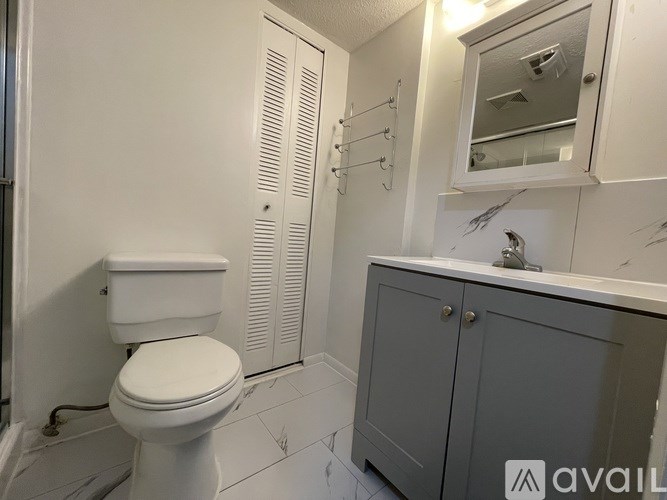 A white toilet sits next to a cabinet with a mirror above it.