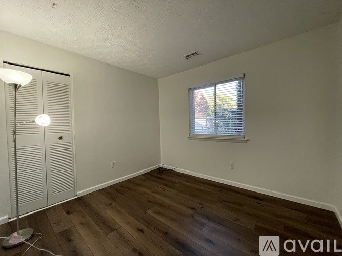 A room with wooden floors and a window with blinds.