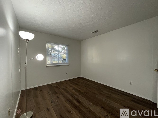 A room with wooden flooring and a window with blinds.