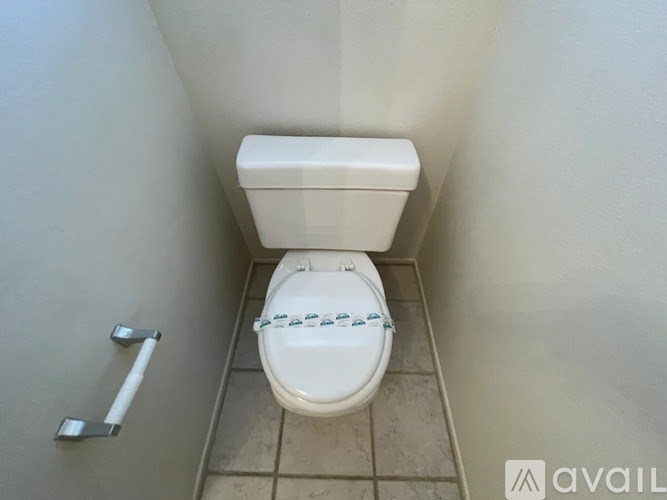 A white toilet with a blue design on the seat lid is in a small bathroom.