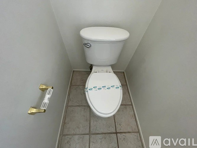 A white toilet with a blue pattern on the lid is in a small bathroom.