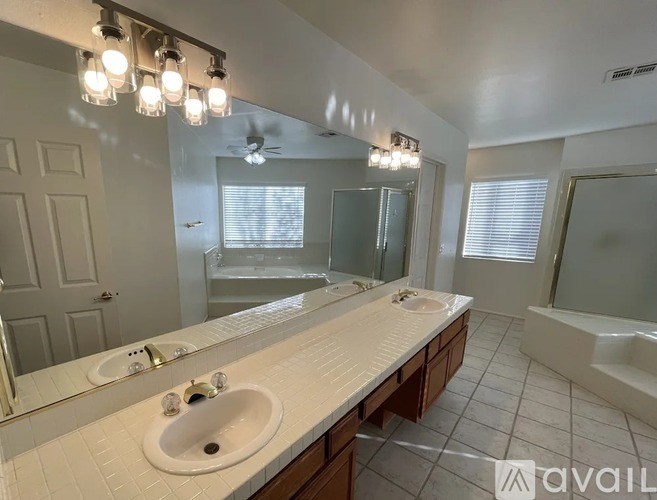 A bathroom with a white countertop and a large mirror above the sink.