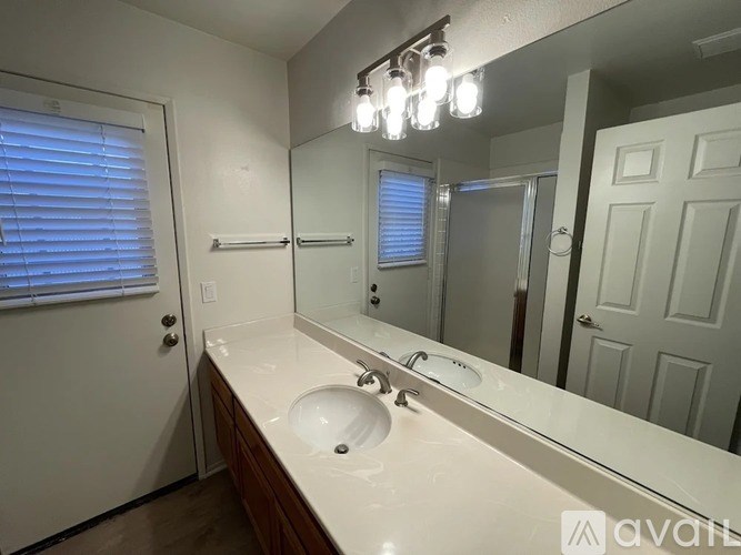 A bathroom with a white countertop and a mirror above it.