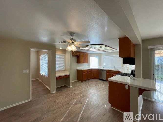 A spacious kitchen and living room with a ceiling fan and wooden flooring.