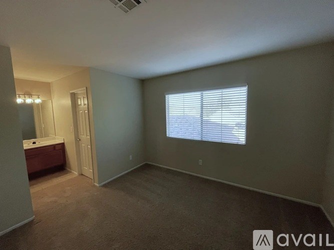 A room with a window covered by blinds, a door, and a bathtub with a shower head.
