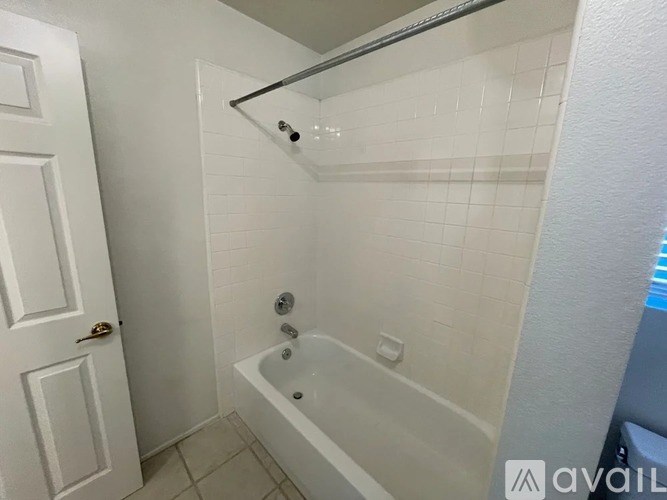 A white bathroom with a tub and a door.