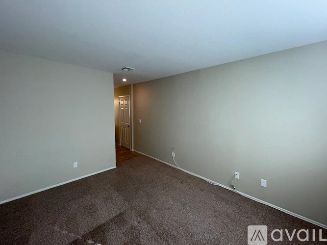A room with a carpeted floor and a doorway leading to another room.