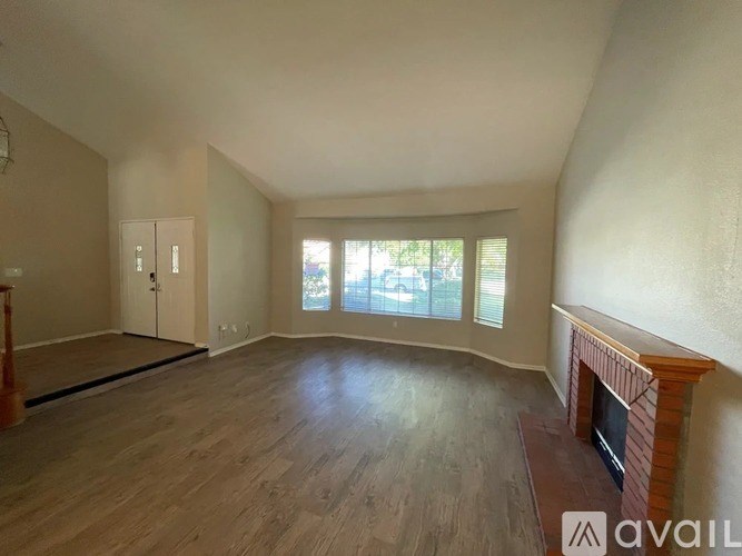A spacious room with wooden flooring and a fireplace.