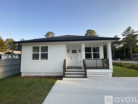A small white house with a black roof and a porch.