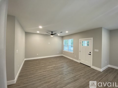 A spacious room with a ceiling fan and wooden flooring.