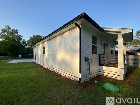 A white house with a black roof and a green frisbee on the grass.