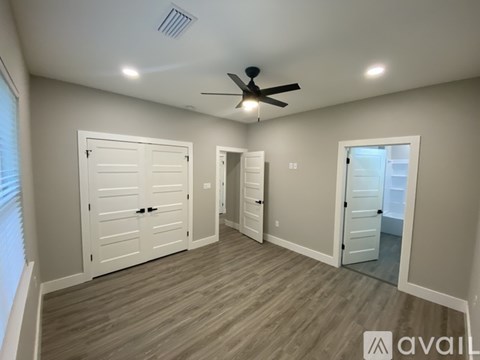 A room with a ceiling fan and three doors.
