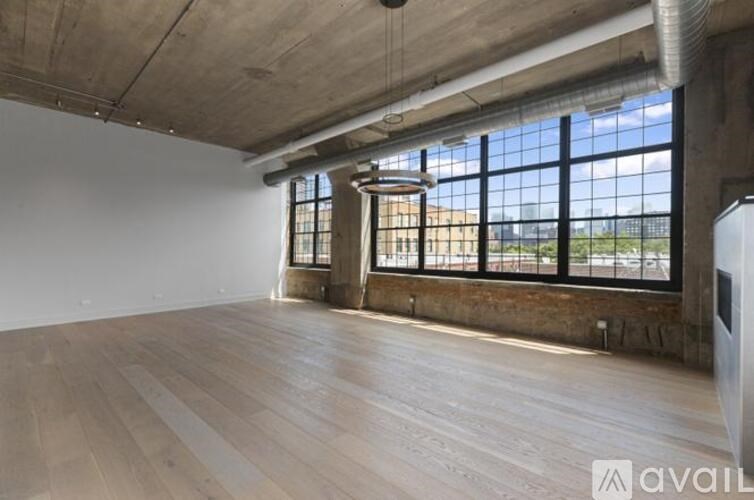 A large empty room with wooden floors and a large window.
