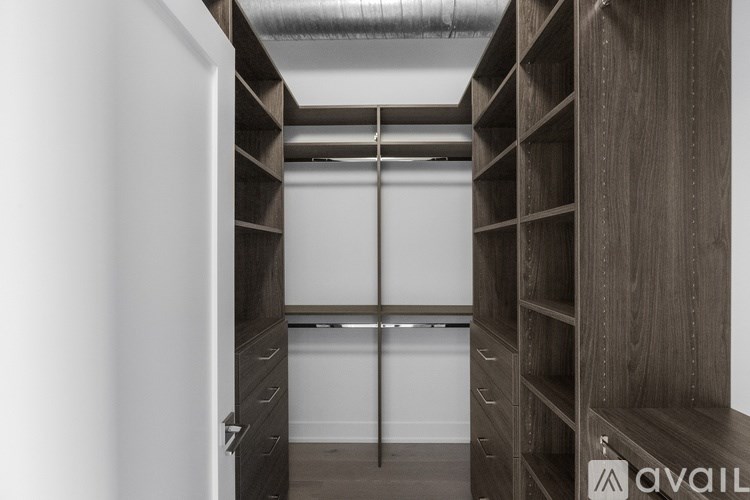 A walk-in closet with wooden shelves and drawers.