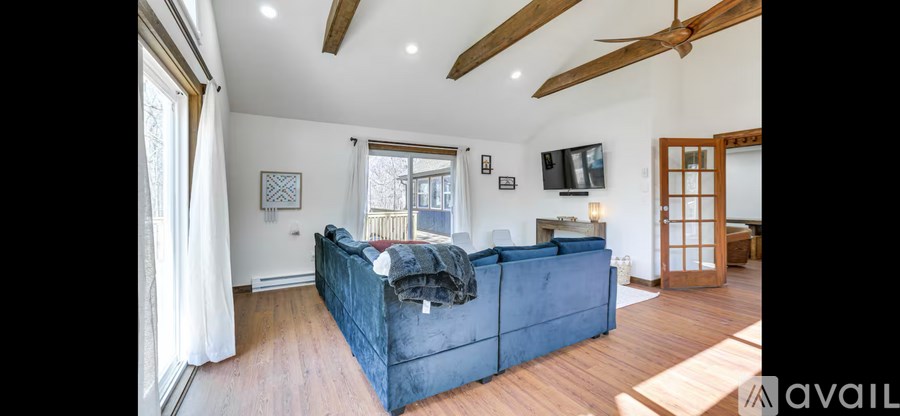 A large blue couch sits in a spacious living room with wooden floors and a high ceiling.