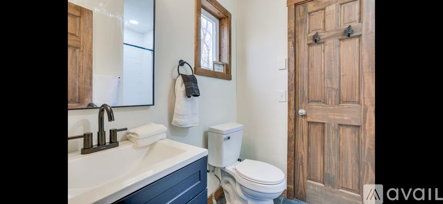 A bathroom with a toilet, sink, and mirror.