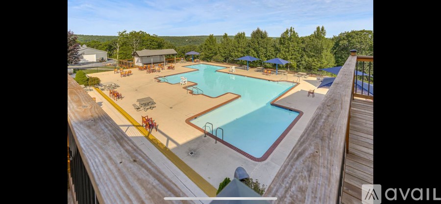 A large outdoor swimming pool with a deck and sunshades.