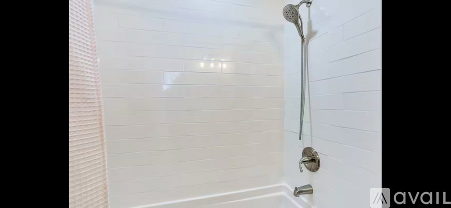 A white tiled shower with a shower head and hand held shower.