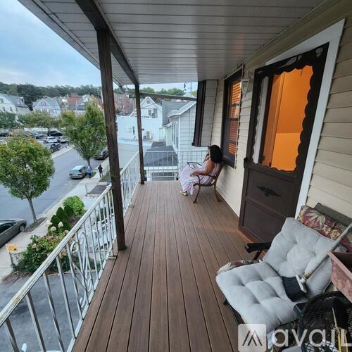 A woman is sitting on a porch with a chair and a table.