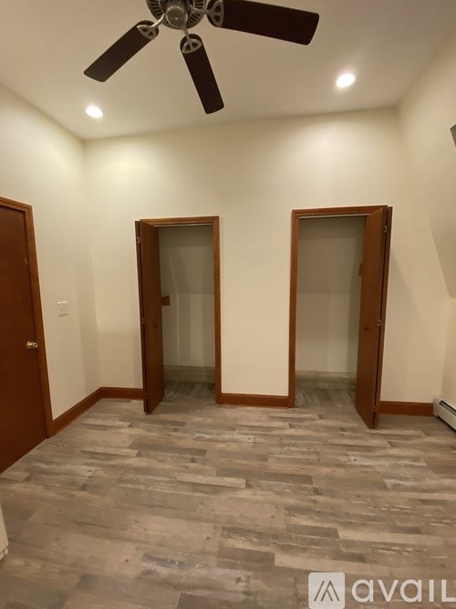 A room with a ceiling fan and two doors.