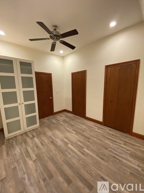 A room with a ceiling fan and wooden flooring.