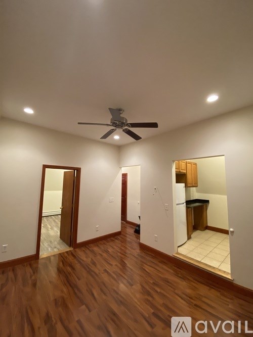 A room with a ceiling fan and wooden flooring.