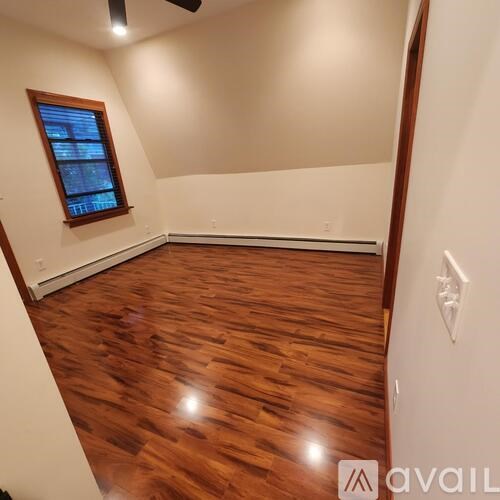 A room with wooden flooring and a window.