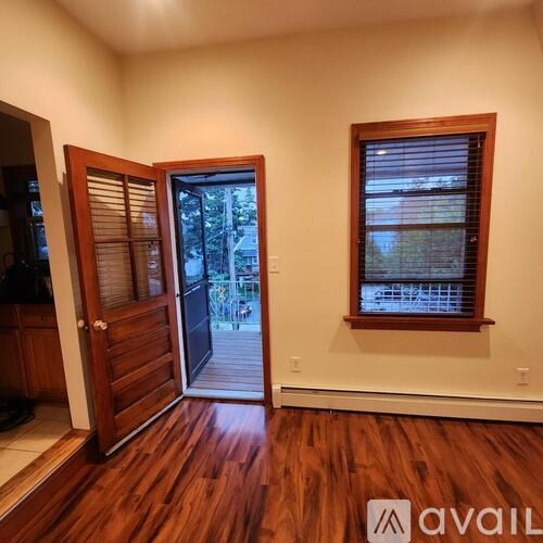 A room with a wooden floor and a window with blinds.