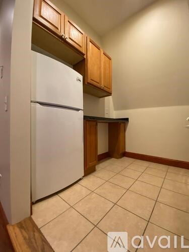 A kitchen with a white fridge and wooden cabinets.