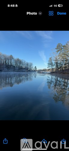 A serene lake surrounded by trees under a clear sky.