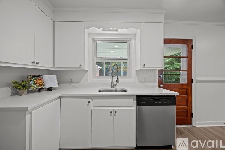 A kitchen with white cabinets and a window.