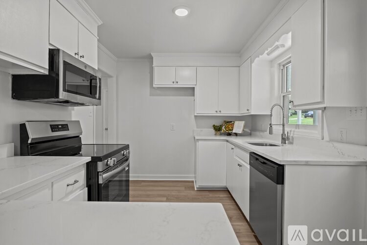 A modern kitchen with white cabinets and black appliances.
