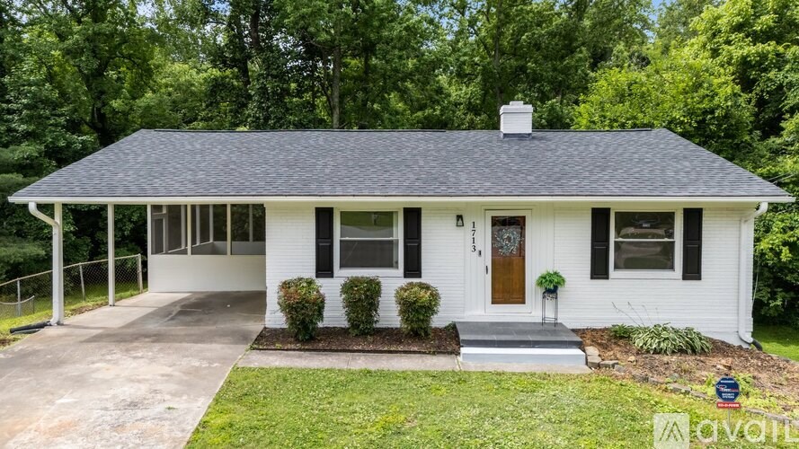 A white house with a black roof and a brown door.