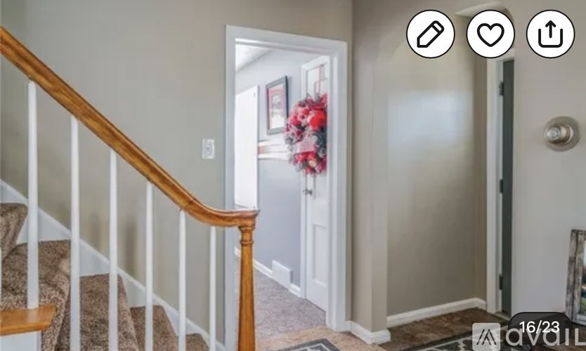 A hallway with a staircase and a door leading to another room.