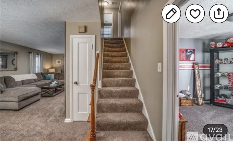 A living room with a couch, a staircase, and a kitchen area in the background.
