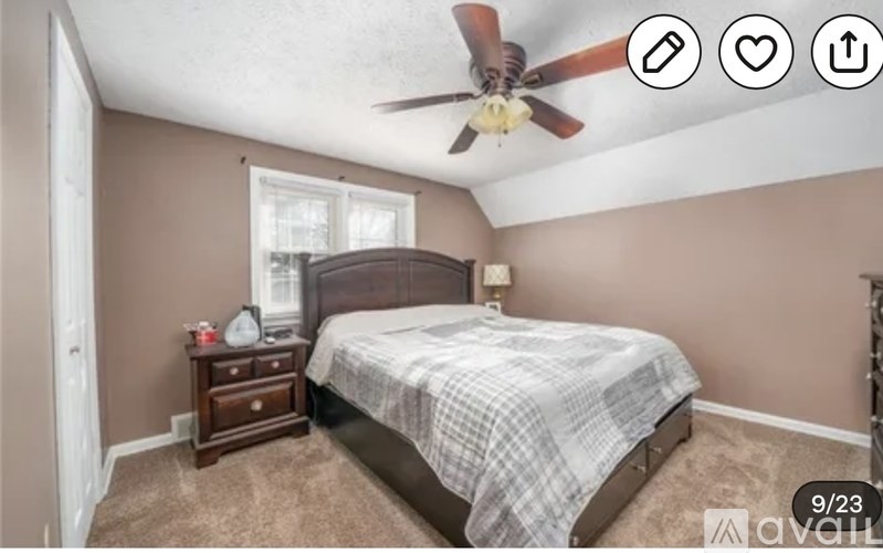 A bedroom with a bed, nightstand, and window.