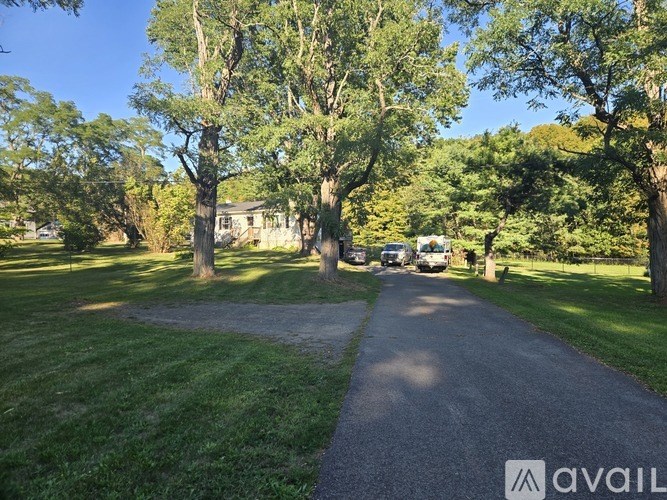A gravel path leads through a grassy area with trees on either side.