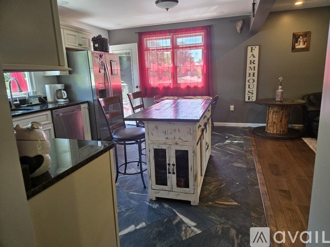 A kitchen with a table and chairs in front of a window with red curtains.