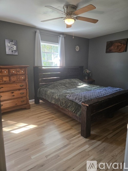 A bedroom with a bed, dresser, and window.