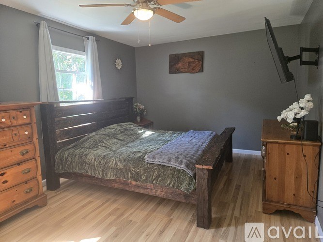 A bedroom with a bed, dresser, and tv.