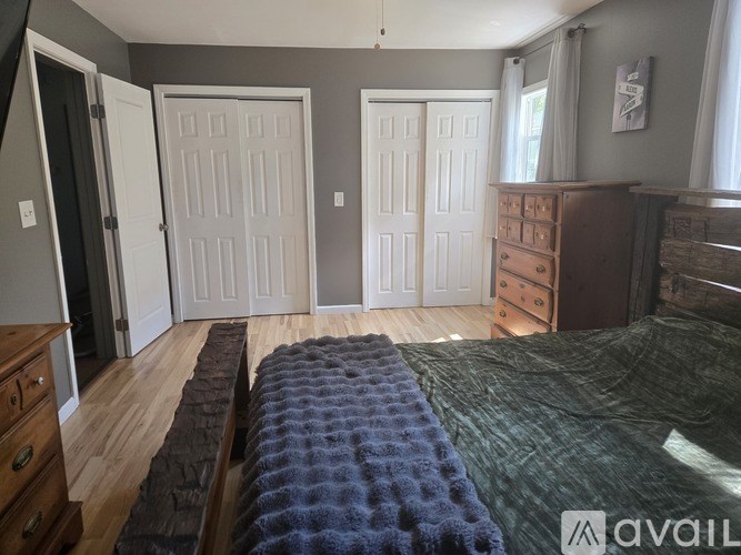 A bedroom with a bed, dresser, and two doors.