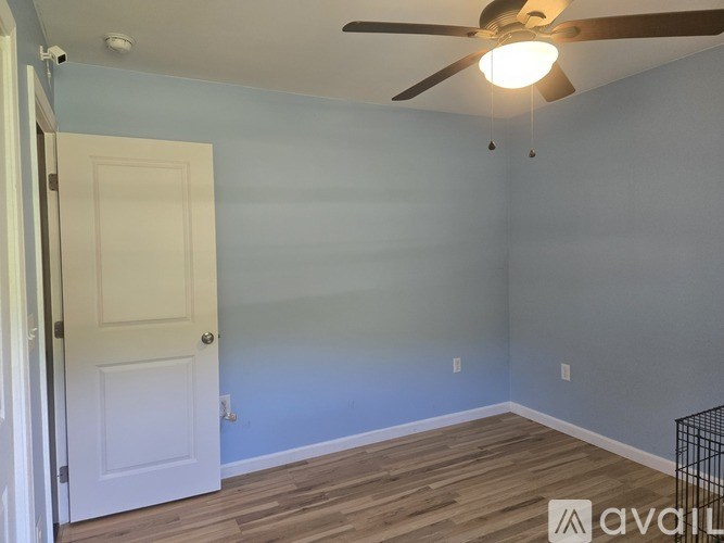 A room with a white door and a ceiling fan.