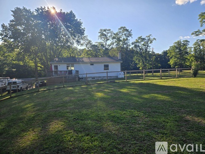 A white house with a fence and trees in the background.