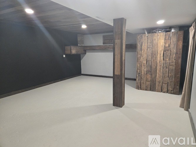 A room with a wooden beam on the wall and a white floor.