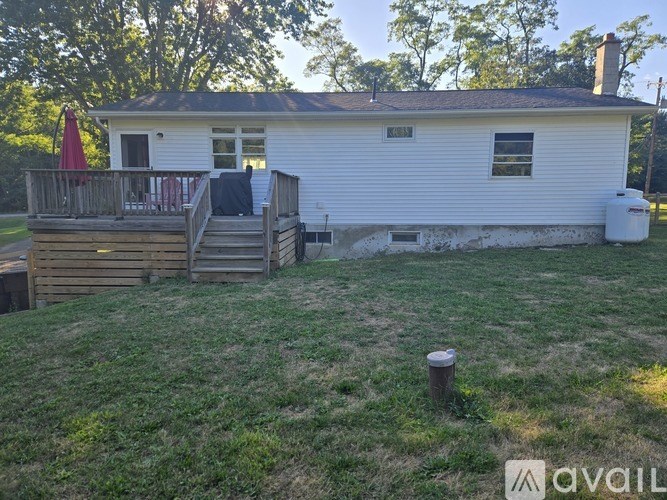 A white house with a deck and a red umbrella.