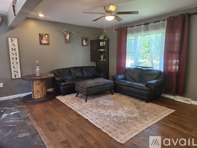A living room with a black leather couch and a wooden coffee table.